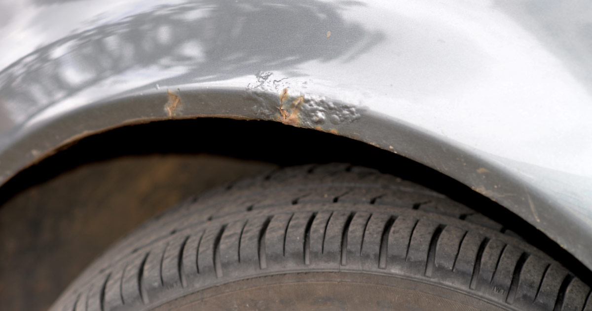 Rust damage to wheel well on silver sedan