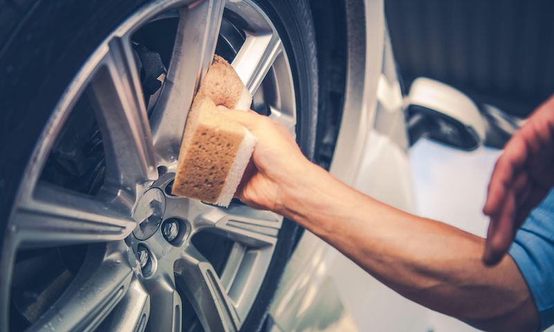 Man Cleaning Wheel with Sponge