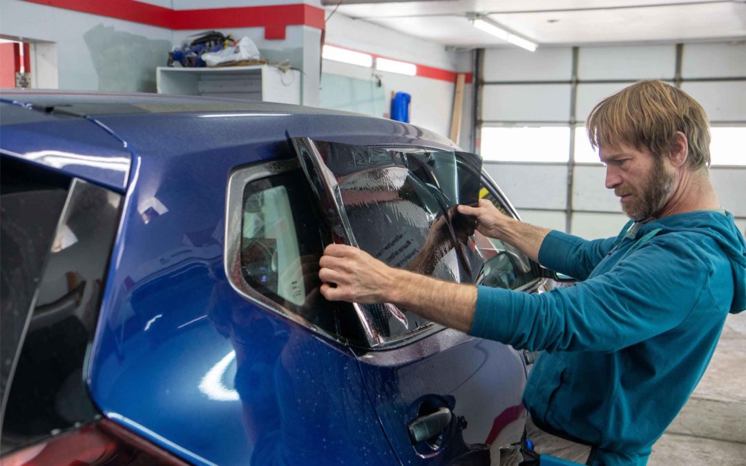 Man Installing Window Tint on Blue SUV
