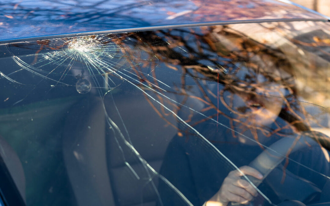 Woman sitting in her car looking out at cracked windshield