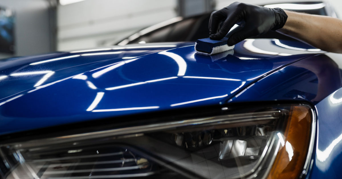 Technician applying ceramic coating on blue sedan