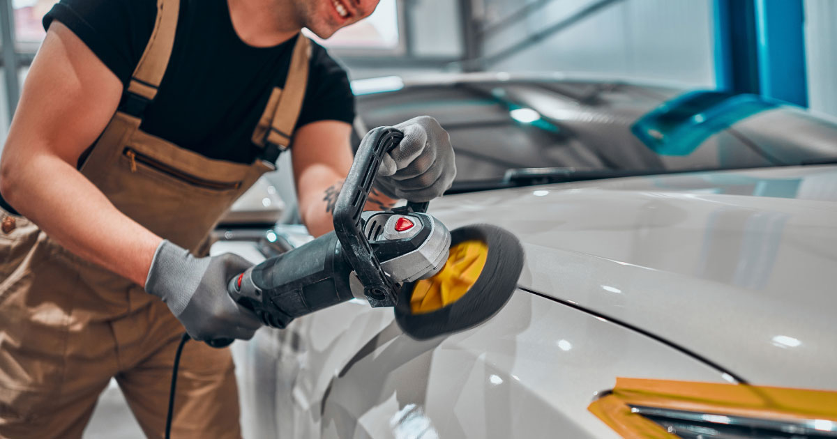 Man buffing paint on white car