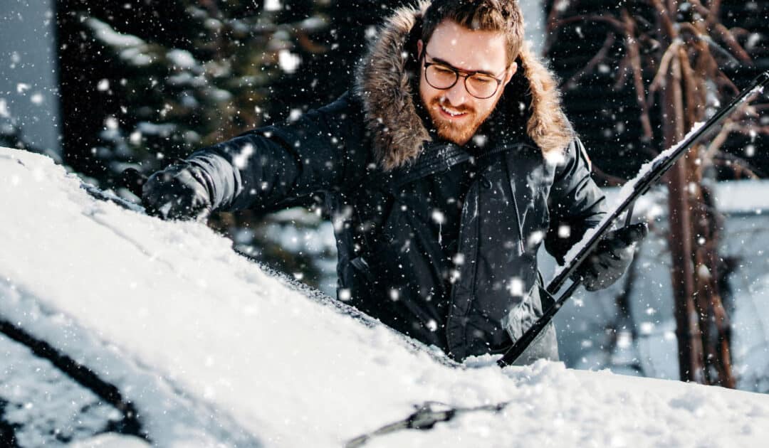 Man clearing ice off of his car's windshield