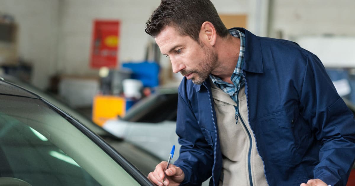 Man inspecting vehicle's windshield