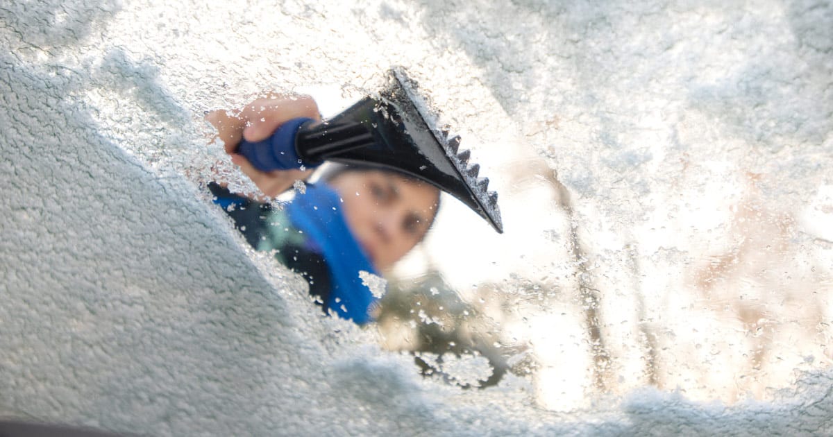 Person using plastic ice scraper on windshield