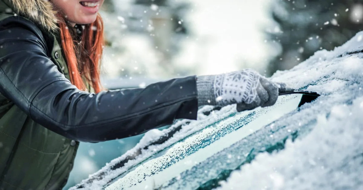 Woman scraping ice off of her windshield