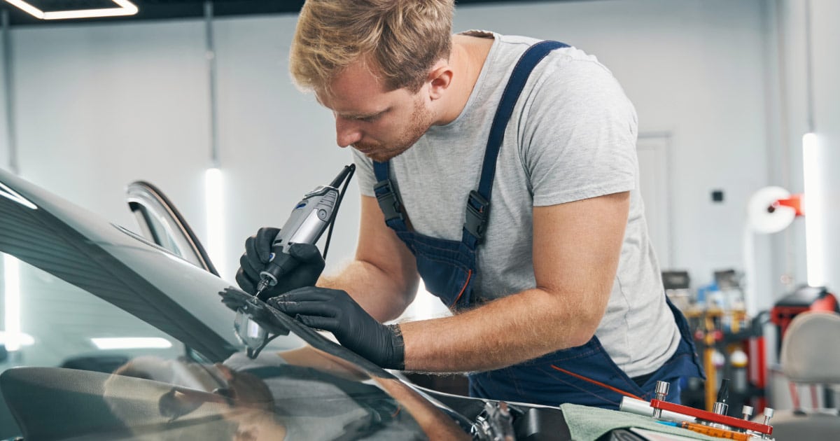Man cleaning out a windshield glass chip during repair